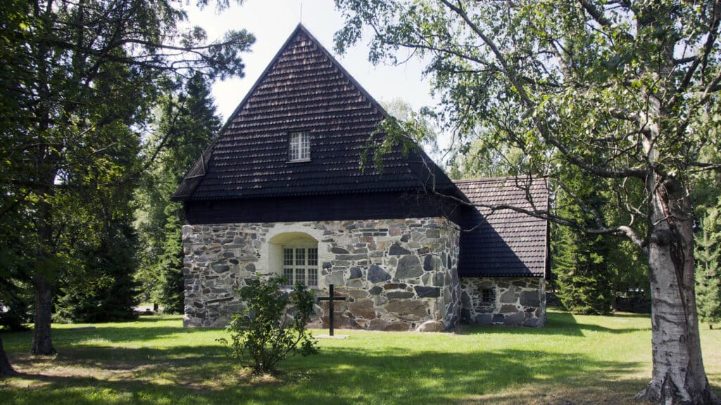 Messukylän vanha kivikirkko kuvattuna ulkoa kirkon pihalta kesällä